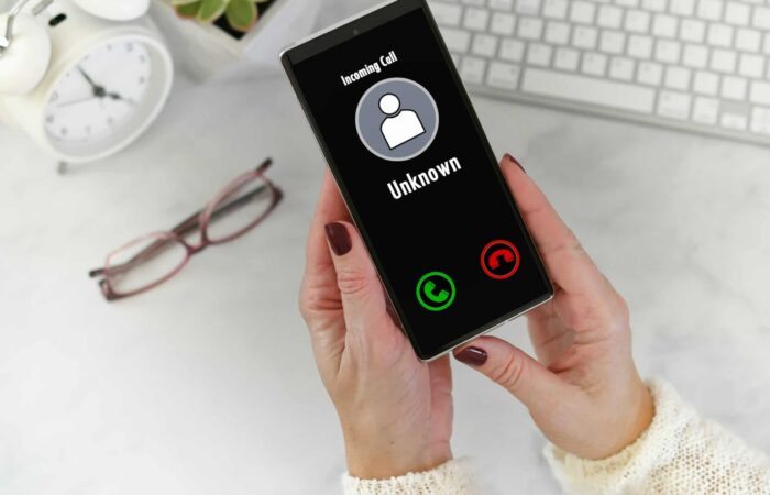 Female hands holding Phone with incoming call from Unknown Caller - fraud scam phishing